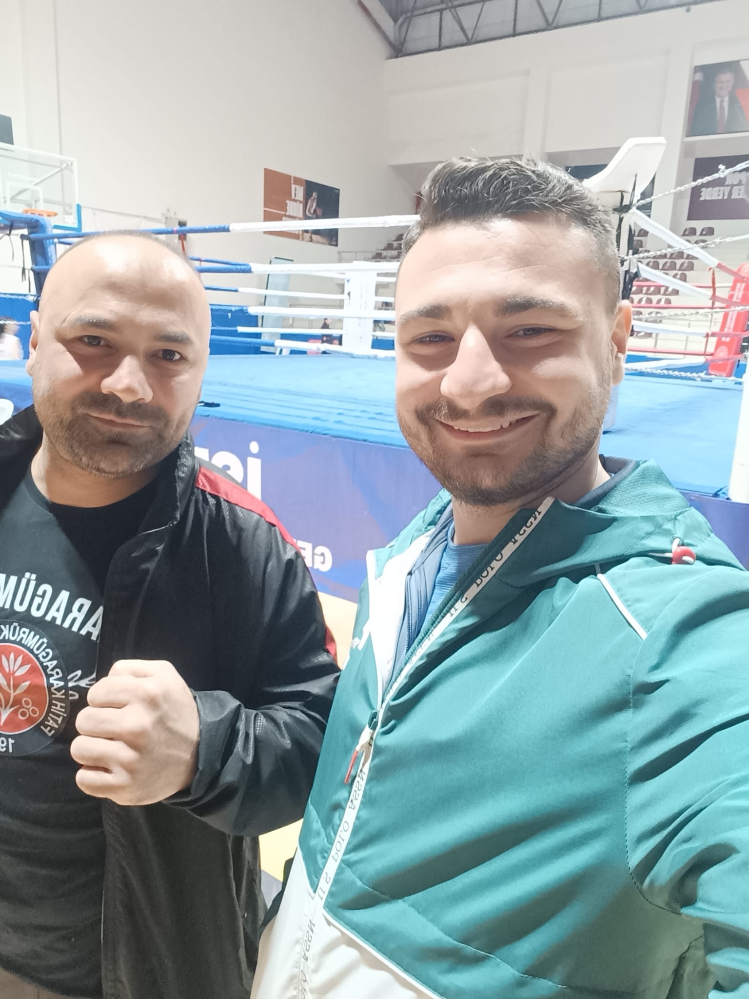 Antrenör ve sporcusu müsabaka salonunda boks ringi önünde